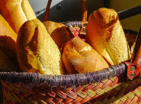Fresh homemade bread under sun light in a wicker basket. Close up.の写真素材