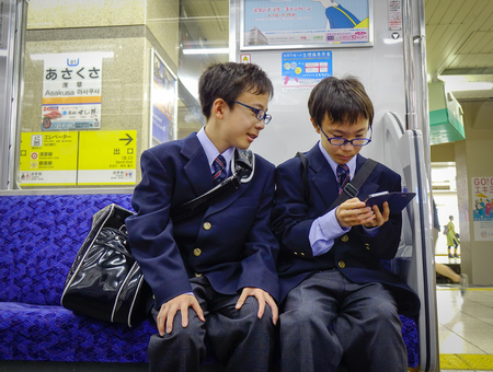 Tokyo, Japan - May 20, 2017. Young students sitting in subway train in Tokyo, Japan. Railways are the most important means of passenger transportation in Japan.のeditorial素材