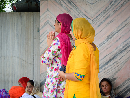 Amritsar, India - Jul 25, 2015. Women praying at the Golden Temple in Amritsar, India. Golden temple...