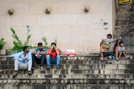 Varanasi, India - Jul 12, 2015. Young people sitting on Ganges riverbank at sunrise in Varanasi, India. Varanasi draws Hindu pilgrims who bathe in the Ganges River sacred waters.のeditorial素材