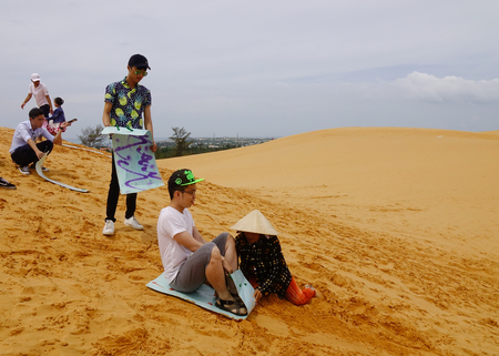 Mui Ne, Vietnam - Jun 3, 2017. Young men playing on the sand dunes in Mui Ne, Vietnam. Sand Dunes just outside of Mui Ne are one of Vietnam charming geological oddities.のeditorial素材