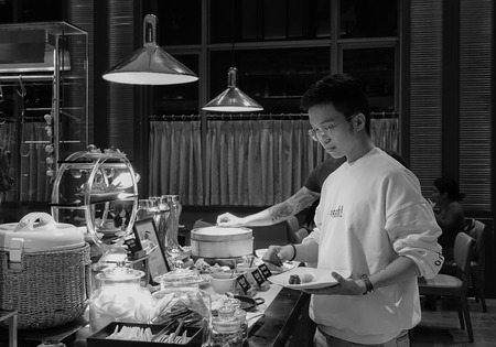 Saigon, Vietnam - May 26, 2017. A man taking food at the buffet restaurant of Sofitel Hotel in Saigon (Ho Chi Minh city), Vietnam.のeditorial素材