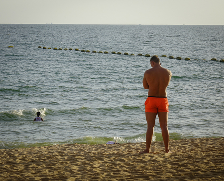 Pattaya, Thailand - Jun 20, 2017. A muscle man standing on Jomtien beach at summer in Pattaya, Thailand. Pattaya is on the east coast of the Gulf of Thailand.のeditorial素材