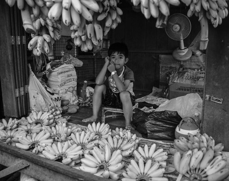 Kampot, Cambodia - Dec 31, 2011. A boy selling banana at rural market in Kampot, Cambodia. Kampot is a small town in south-east Cambodia, and is a gateway to Bokor National Park.のeditorial素材