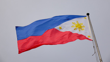 Philippines flag waving in the sky at downtown in Manila, Philippines.の写真素材