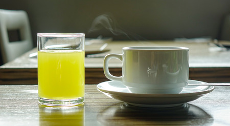 Cup of coffee with glass of fruit juice on the table for breakfastの写真素材