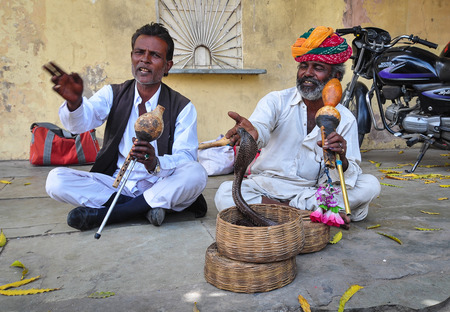 Jaipur, India - Mar 7,2012. Snake charmers at the street of Jaipur, India. Snake charmers pretending to hypnotise a snake by playing an instrument called pungi.のeditorial素材