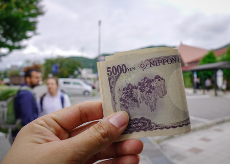 Hand hold Japanese banknotes (yen-JPY) at bus station in Nagano, Japan.の写真素材