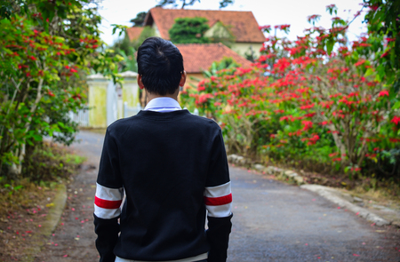 An Asian young man walking at the botanic garden in spring time.の写真素材