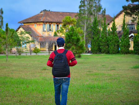 An Asian young student standing in campus outdoors.