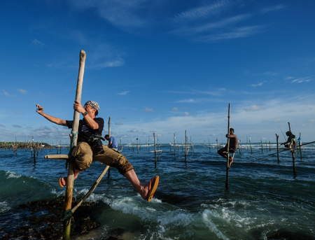 Hikkaduwa, Sri Lanka - Sep 9, 2015. A photographer taking pictures of traditional fishermen on the sea in Hikkaduwa, south west Sri Lanka.のeditorial素材