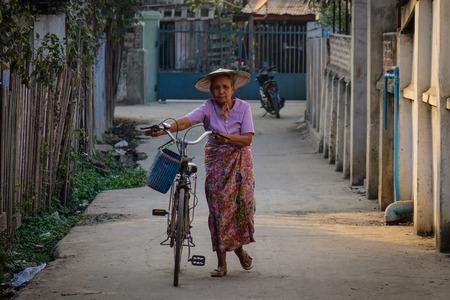 Hsipaw, Myanmar - Feb 23, 2016. A woman with bicycle on street in Hsipaw, Shan State, Myanmar. Shan is Burma largest ethnic nationality group.のeditorial素材