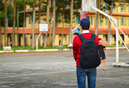 Young student standing at basketball yard of old college in Dalat, Vietnam.のeditorial素材