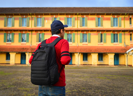 A young student with backpack standing at an old college.の写真素材