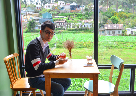 An Asian man at a coffee shop with nature background.のeditorial素材