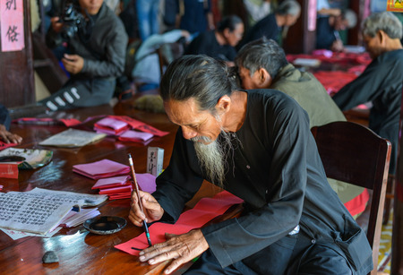 Vung Tau, Vietnam - Feb 6, 2018. Local men writing Chinese calligraphy on red paper at an old village in Vung Tau, Vietnam.のeditorial素材