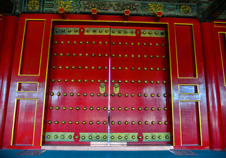 Ornate red wooden door with tile trim at the Forbidden City in Beijing, China.のeditorial素材