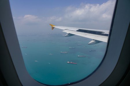Airplane flying over the Singapore sea, view from airplane window.の写真素材