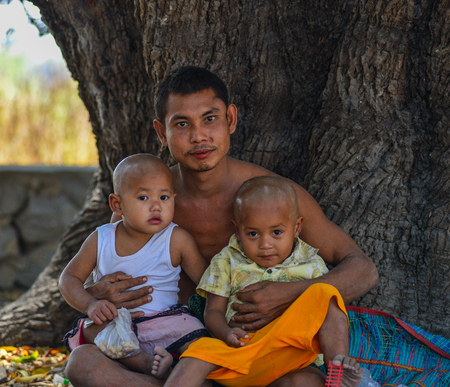 Mandalay, Myanmar - Feb 11, 2017. A young man with his children relaxing at the park in Mandalay, Myanmar.のeditorial素材