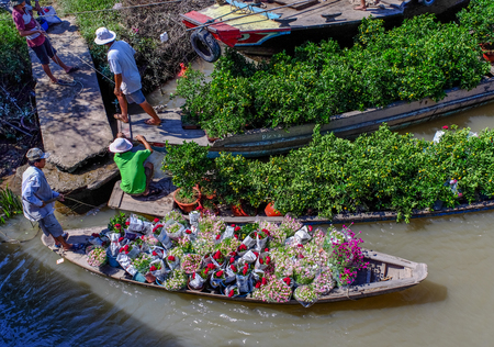 Can Tho, Vietnam - Jan 31, 2016. People carrying flowers by wooden boat on Mekong River in Can Tho, Vietnam.のeditorial素材
