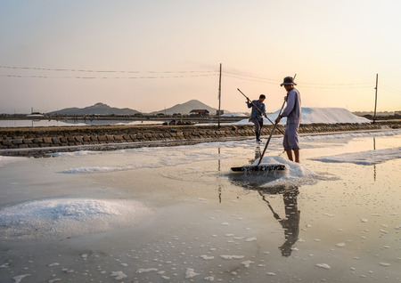 Nha Trang, Vietnam - Mar 21, 2016. People working on salt field at sunrise in Nha Trang, Vietnam....