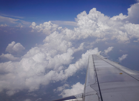 Wing of an airplane flying in blue sky.