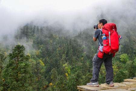 Pokhara, Nepal - Oct 22, 2017. Traveler with backpack in mountains enjoying on view of foggy karst mountains.のeditorial素材