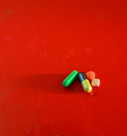 Medical or vitamin pills on red background. Colorful pill texture.の写真素材