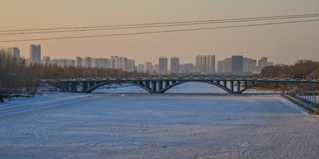 Harbin, China - Feb 22, 2018. The bridge on ice river at sunset in Harbin, China. Harbin is largest city in the northeastern region of China.のeditorial素材
