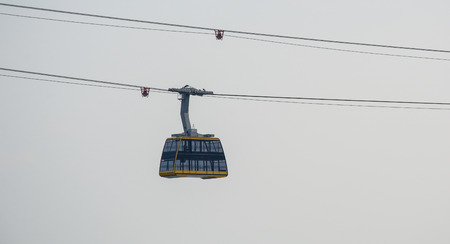 Cabin of the cable car against gray sky in misty day.