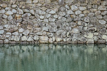 Stone wall of ancient castle with the moat in Himeji, Japan.の写真素材