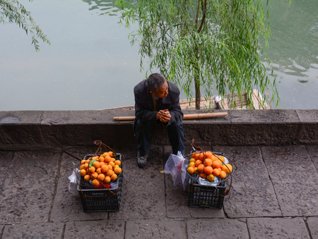 Hunan, China - Nov 5, 2015. Vendors selling fruits on street at Fenghuang Ancient Town in Hunan, China.のeditorial素材