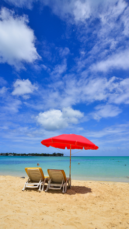 Relaxing chairs and red umbrella on beach in Grand Baie, Mauritius. Mauritius is a major tourist destination, ranking 3rd in the region.のeditorial素材