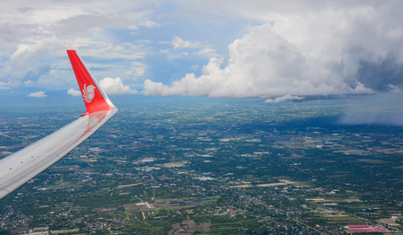 Chiang Mai, Thailand - Jun 22, 2016. Wing of an airplane flying above countryside in sunny day.のeditorial素材