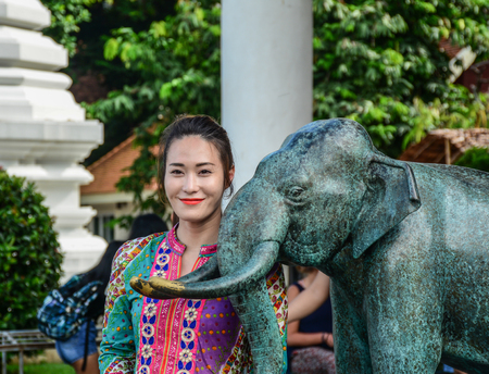 Young woman with stone elephant statue in Buddhist temple.のeditorial素材