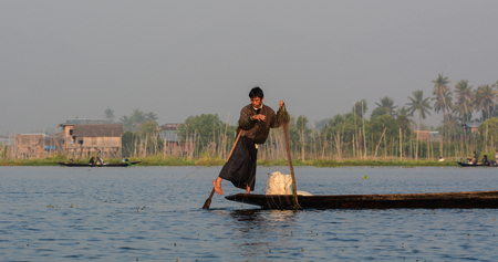 Inle, Myanmar - Feb 14, 2016. Burmese man using the unique methods of rowing and catching fish on Inle Lake. Inle is one of the highest lake at an elevation of 880m.のeditorial素材