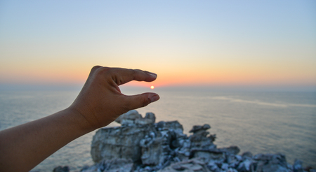 A hand with the sun in sunset. Nature background.の写真素材