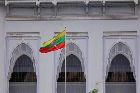 Myanmar national flag with old building (Yangon City Hall) background.