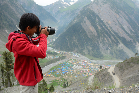 Srinagar, India - Jul 2, 2015. Young traveler taking pictures on mountain in Srinagar, India. Srinagar is the largest city and the summer capital of Jammu and Kashmir.のeditorial素材
