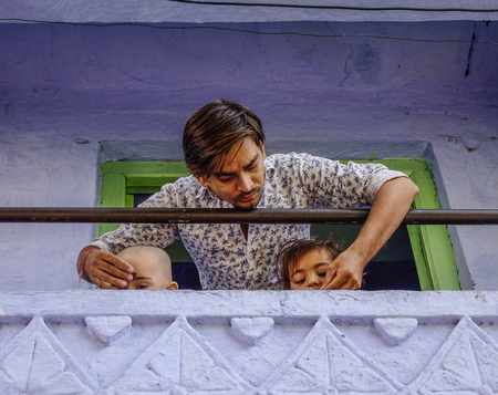 Jodhpur, India - Nov 6, 2017. A young man with his children at rural house in Jodhpur, India. Jodhpur is the second largest city in state of Rajasthan.のeditorial素材