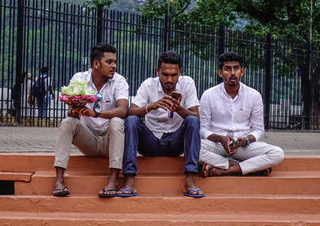 Kandy, Sri Lanka - Dec 15, 2018. Local young men sitting at Temple of the Sacred Tooth Relic in...