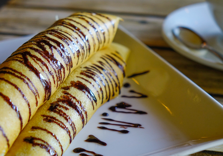 Delicious pancakes with chocolate sauce and banana on wooden board.の写真素材