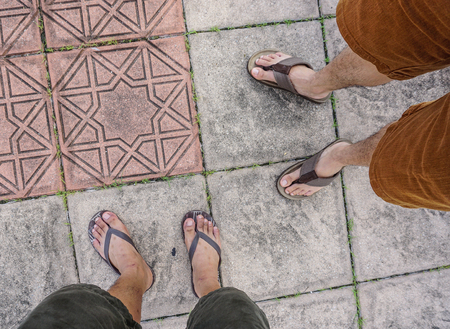 Male foot with flip flop shoes on road in George Town, Malaysia.
