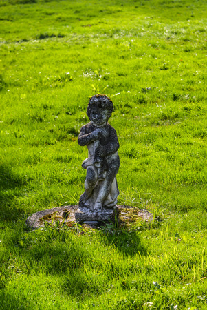Statue of a child angel made of light stone in sunny day.の写真素材