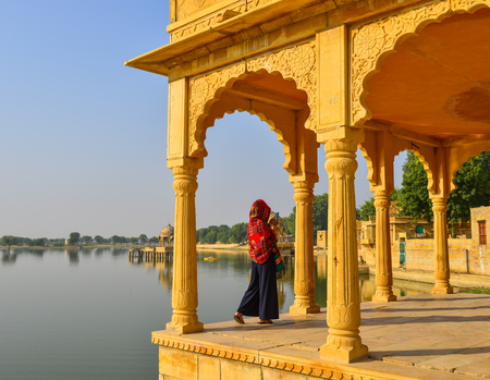 A young woman standing and looking at the lake in sunny day.の写真素材