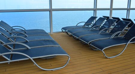 Empty sunbed lounge chairs for relaxing on the open deck of a cruise ship.
