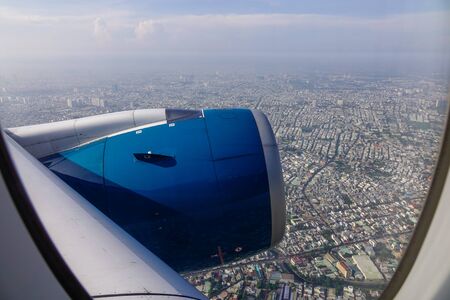 Blue engine of passenger airplane with cityscape background in sunny day.