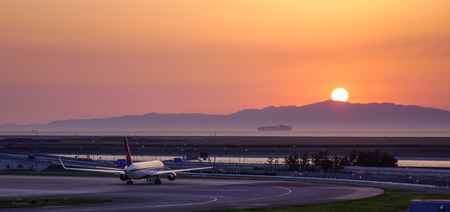 Osaka, Japan - Apr 19, 2019. Passenger airplanes taxiing on runway of Kansai Airport (KIX) in sunset.のeditorial素材