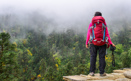 Pokhara, Nepal - Oct 20, 2017. A trekker with backpack looking at the misty forest on mountain in Annapurna Range, Nepal.のeditorial素材