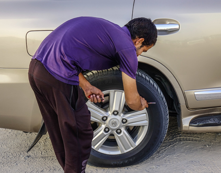 Dubai, UAE - Dec 5, 2018. A man working with a car wheel on Dubai desert. Driving on the desert is...